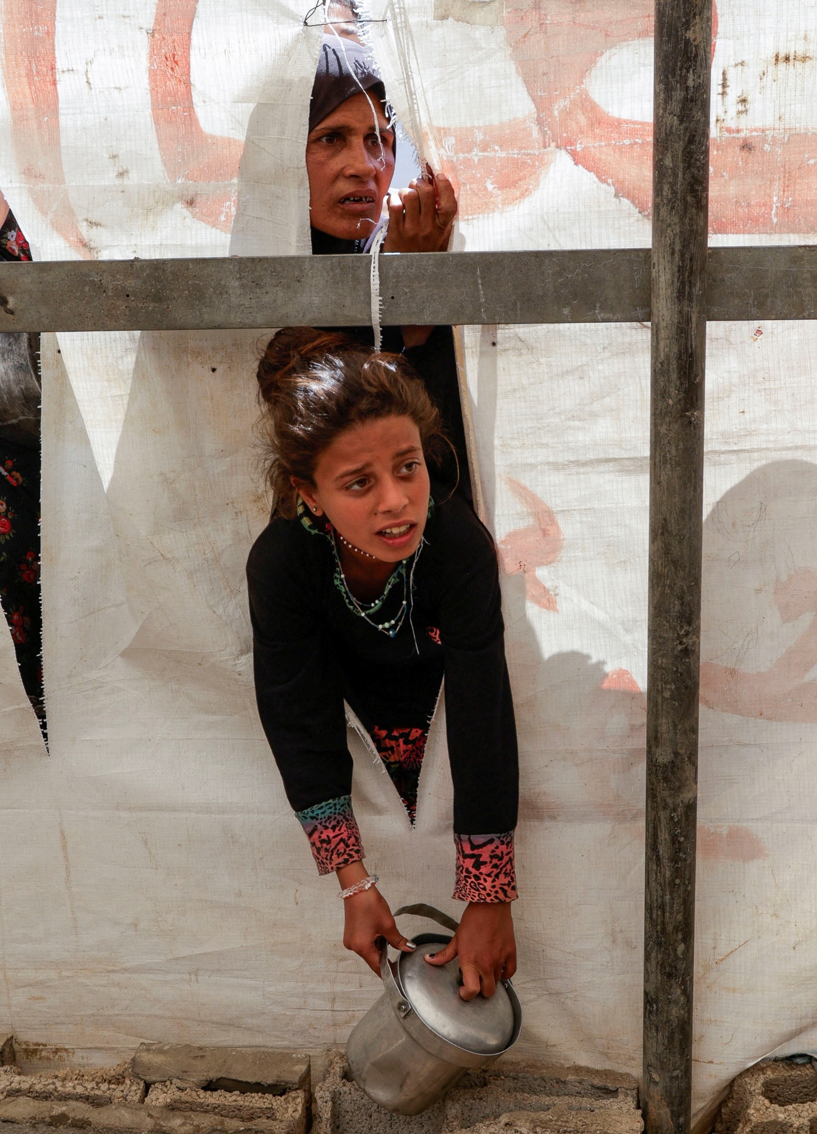 فتاة فلسطينية ووالدتها تنتظران الحصول على الطعام الذي أعدته جمعية خيرية في خان يونس جنوب قطاع غزة. 29 أبريل 2025