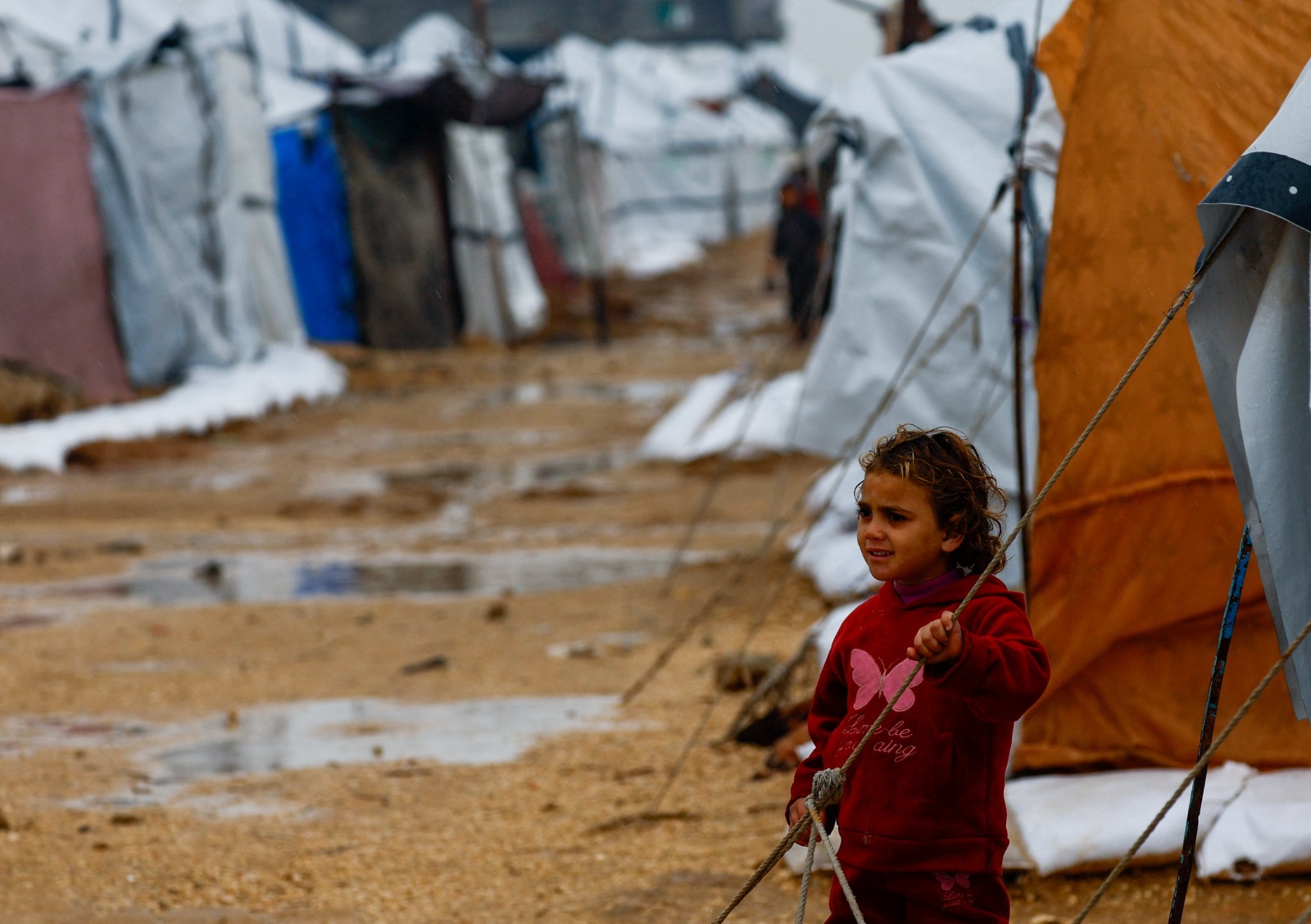 طفلة فلسطينية نازحة في مخيم خلال يوم ممطر في النصيرات وسط قطاع غزة. 11 ديسمبر 2025