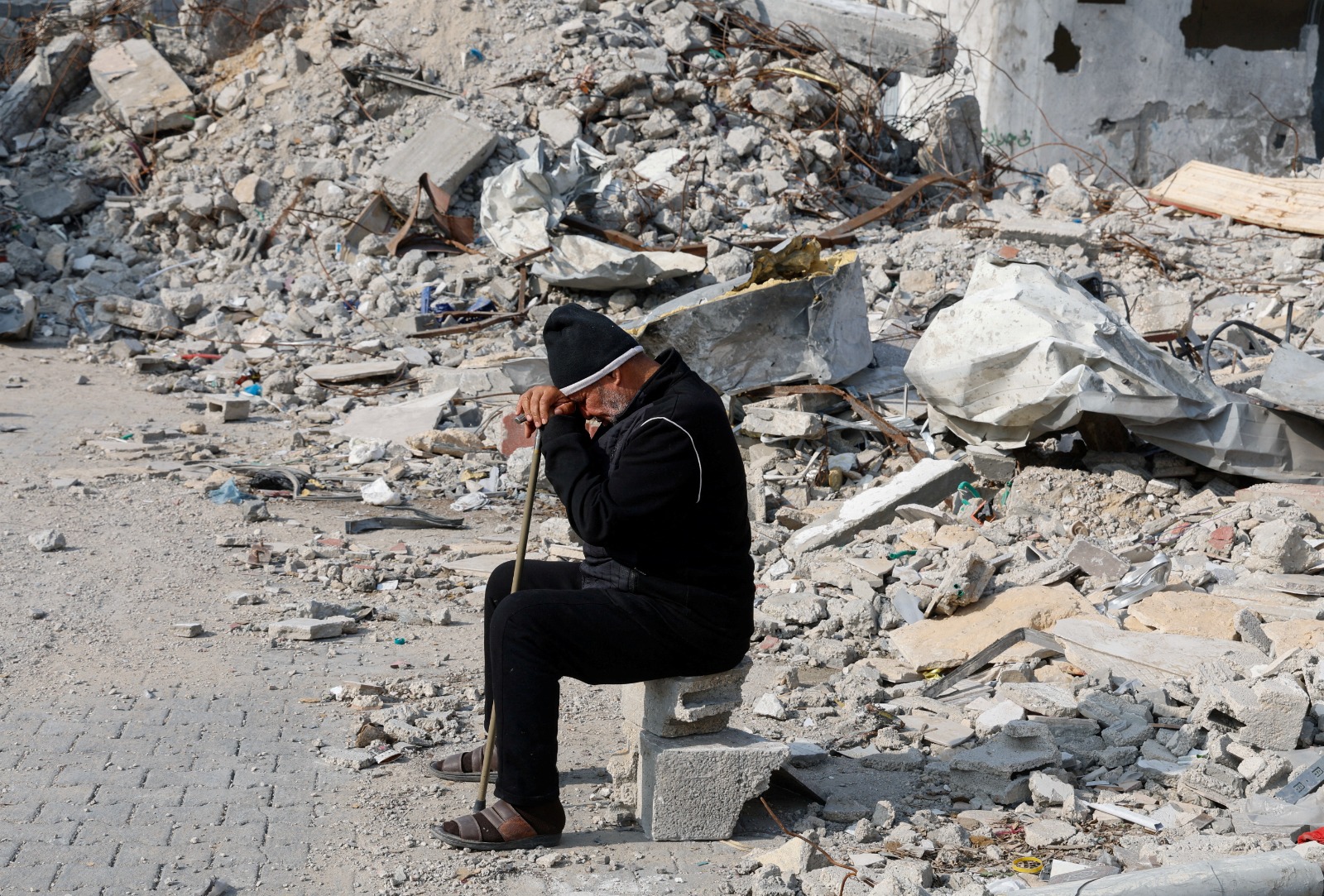 رجل فلسطيني يجلس قرب أنقاض منزل دمرته غارة إسرائيلية في رفح بجنوب قطاع غزة- 9 يناير 2024