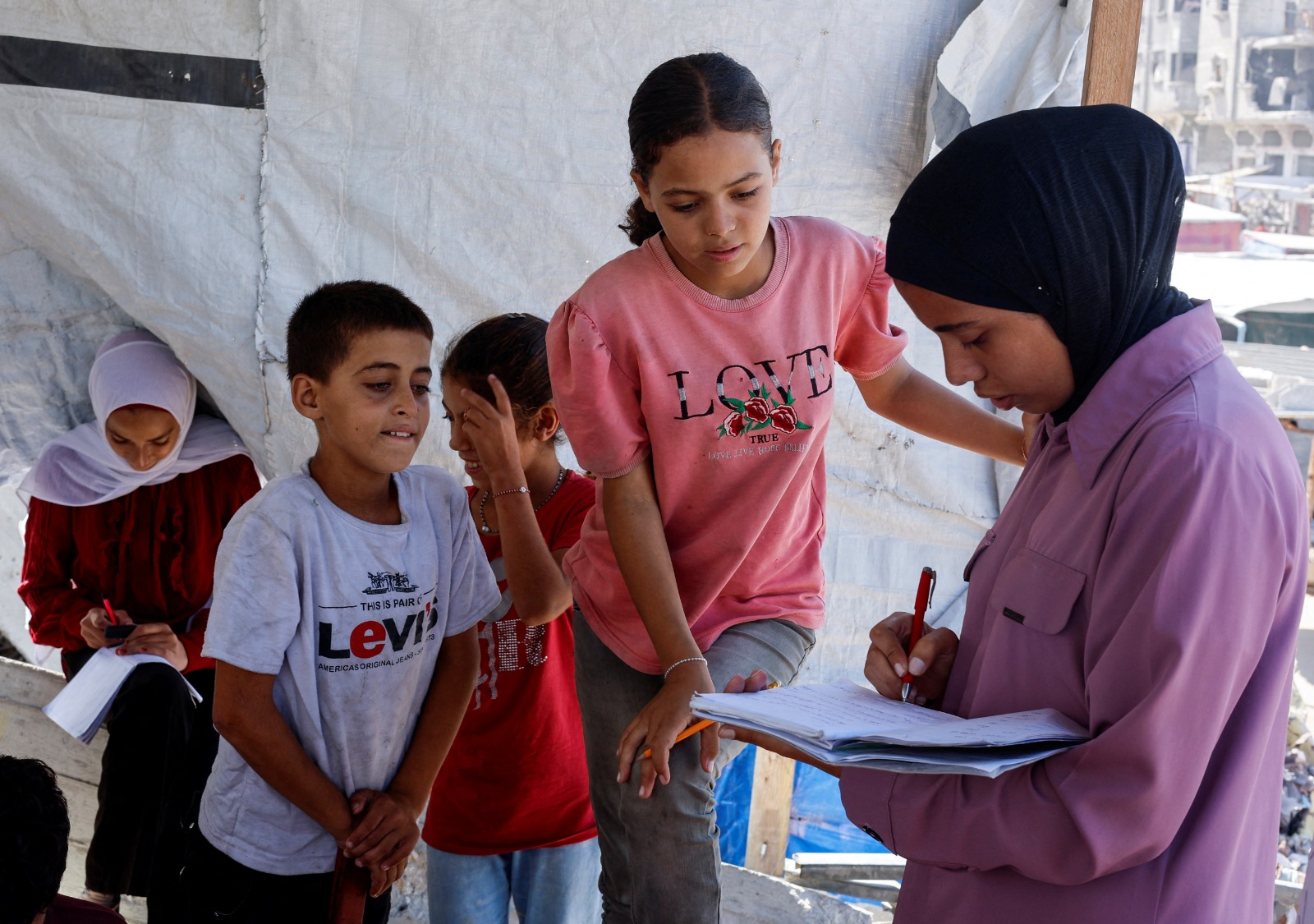 طلاب فلسطينيون يحضرون درساً في خيمة أقيمت على أنقاض منزل معلمة في خان يونس جنوب قطاع غزة. 10 أكتوبر 2024