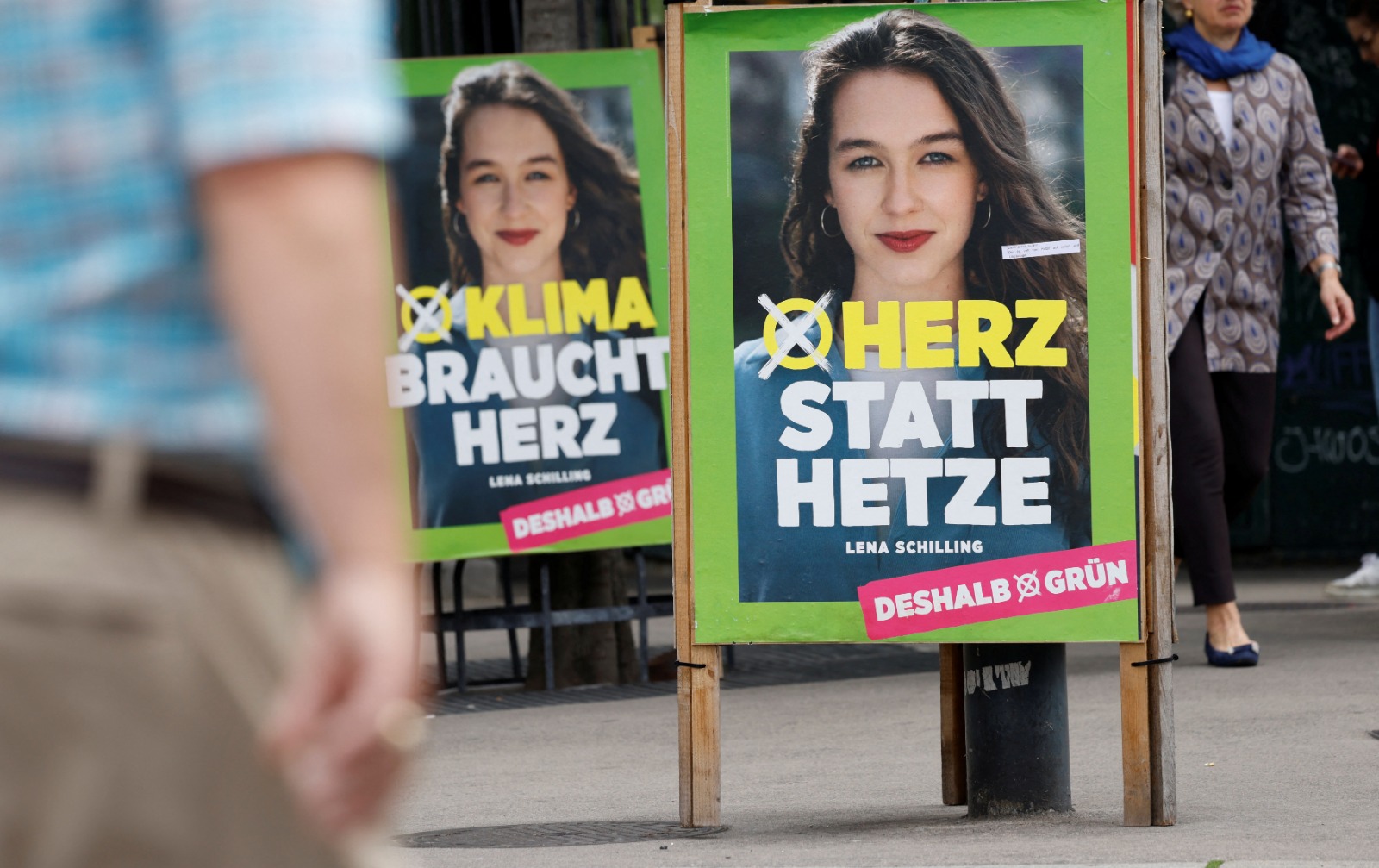 أشخاص يمررون ملصقا للحملة الانتخابية، يظهر المرشحة الأولى لينا شيلينج من حزب الخضر للانتخابات الأوروبية المقبلة لعام 2024 في فيينا، النمسا، 22 مايو 2024