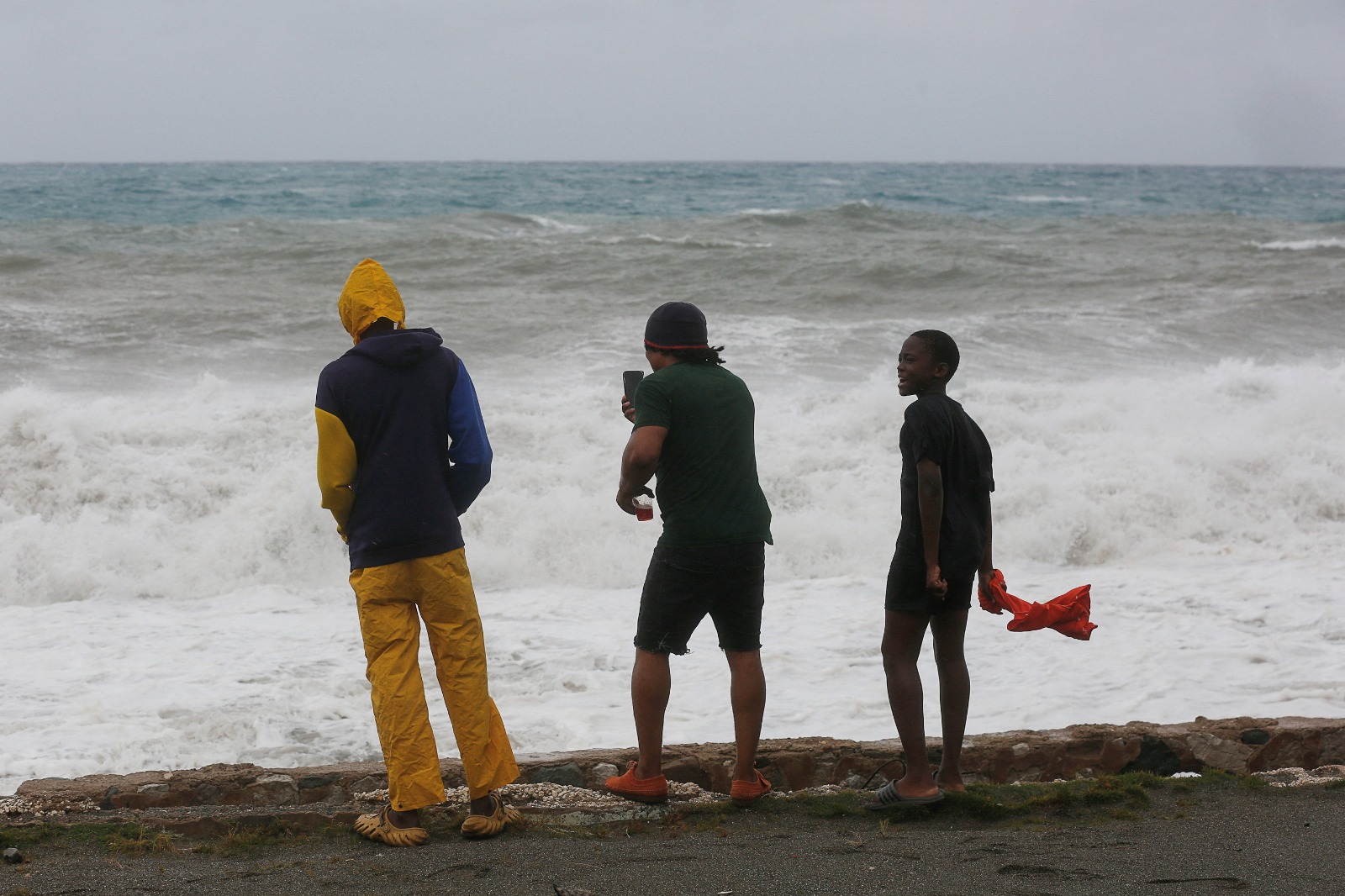 أشخاص يتابعون الأمواج وهي تتكسر بعنف مع اقتراب الإعصار ميليسا، في حي هاربر فيو بمدينة كينجستون، جامايكا. 27 أكتوبر 2025