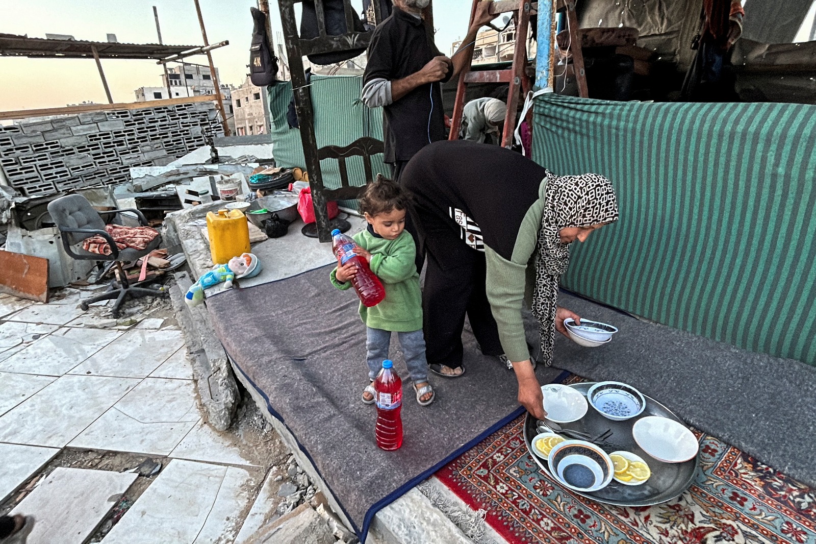 أسرة فلسطينية تجهز وجبة إفطار على ركام منزلها الذي دمرته الغارات الإسائيلية على بيت لاهيا شمال قطاع غزة. 14 مارس 2024