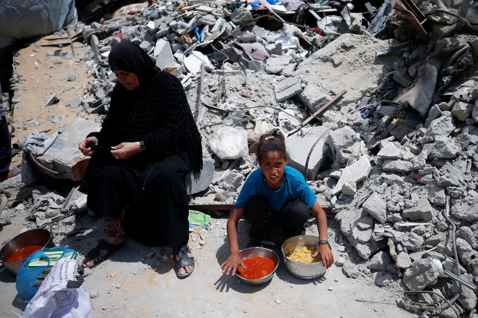 امرأة فلسطنية وبجانبها فتاة بعد حصولهما على طعام أعدته جمعية خيرية في بيت لاهيا شمال قطاع غزة. 28 أبريل2025