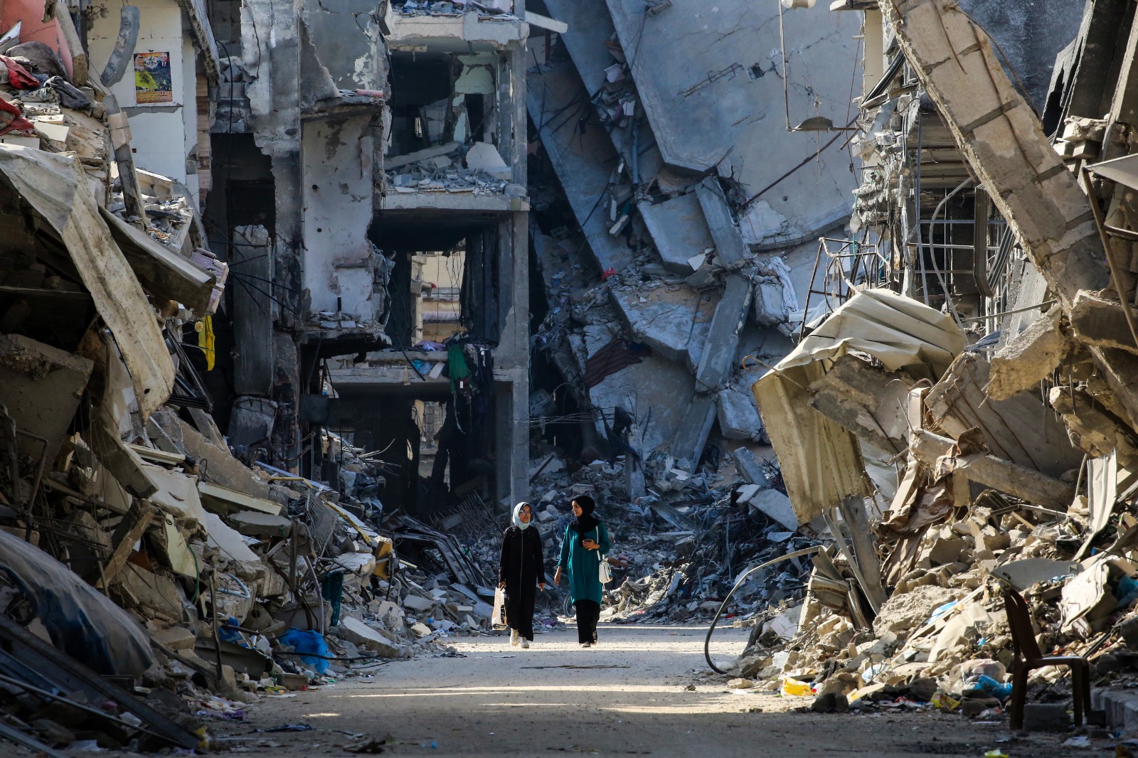 فلسطينيتان تسيران وسط مباني مدمرة جراء القصف الإسرائيلي على خان يونس، قطاع غزة. 20 يونيو 2024