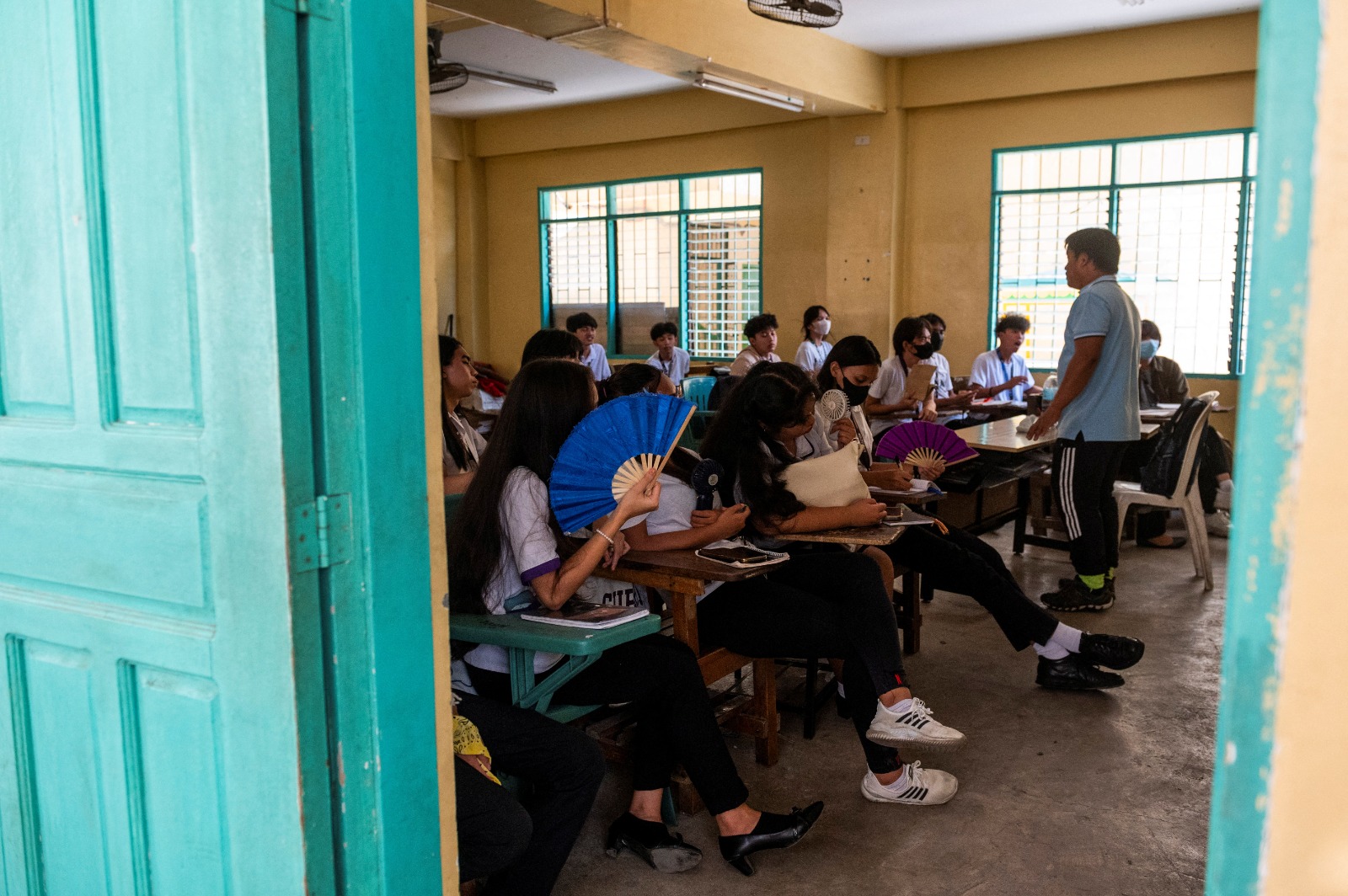 طلاب يستخدمون مراوح يدوية أثناء حضورهم لفصل دراسي في مدرسة بالعاصمة الفلبينية مانيلا. 18 أبريل 2024
