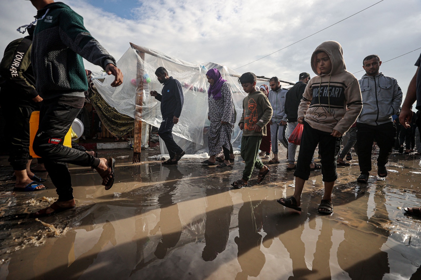 نازحون فلسطينيون في غزة يحاولون تفادي مياه الأمطار داخل مخيم لإيواهم وسط القصف الإسرائيلي المستمر على القطاع. 15 نوفمبر 2023