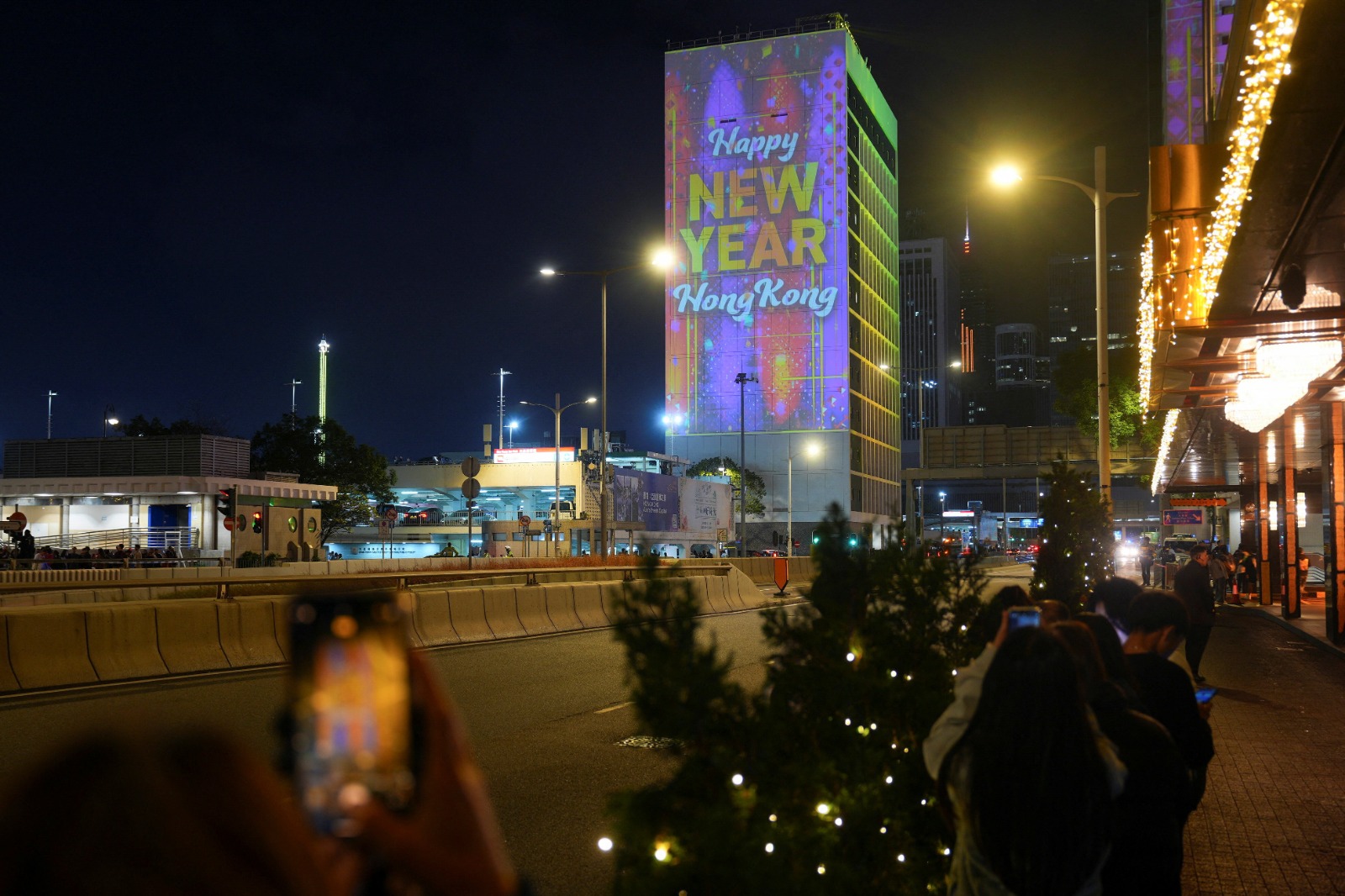 أشخاص يلتقطون صورًا لشاشة يتم عرضها أعلى مبنى بلدية هونج كونج للاحتفال بالعام الجديد في سنترال في هونج كونج، الصين. 1 يناير 2026