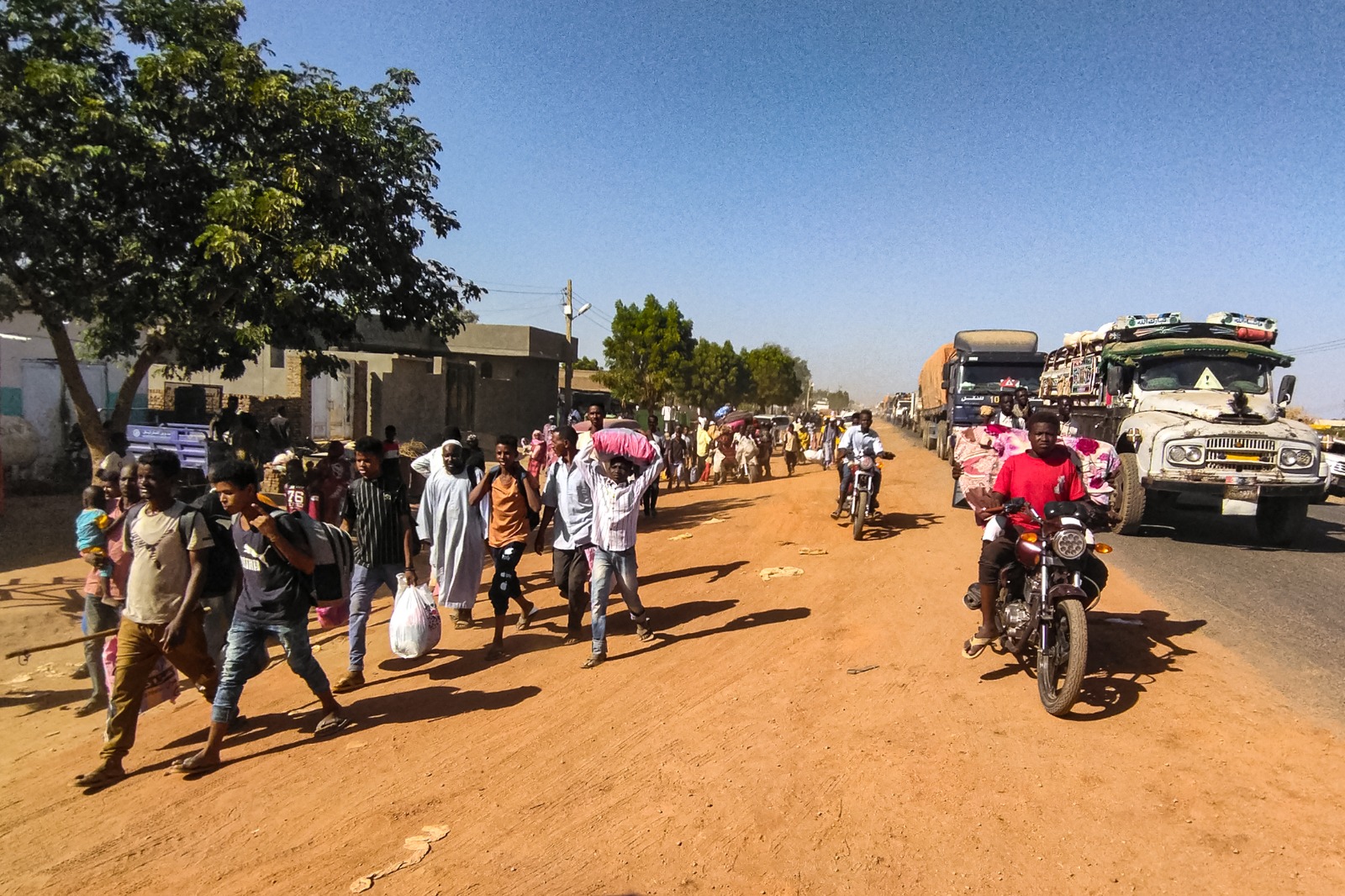 سودانيون نازحون يحملون أمتعتهم على طول طريق بمدينة ود مدني عاصمة ولاية الجزيرة في السودان. 16 ديسمبر 2023