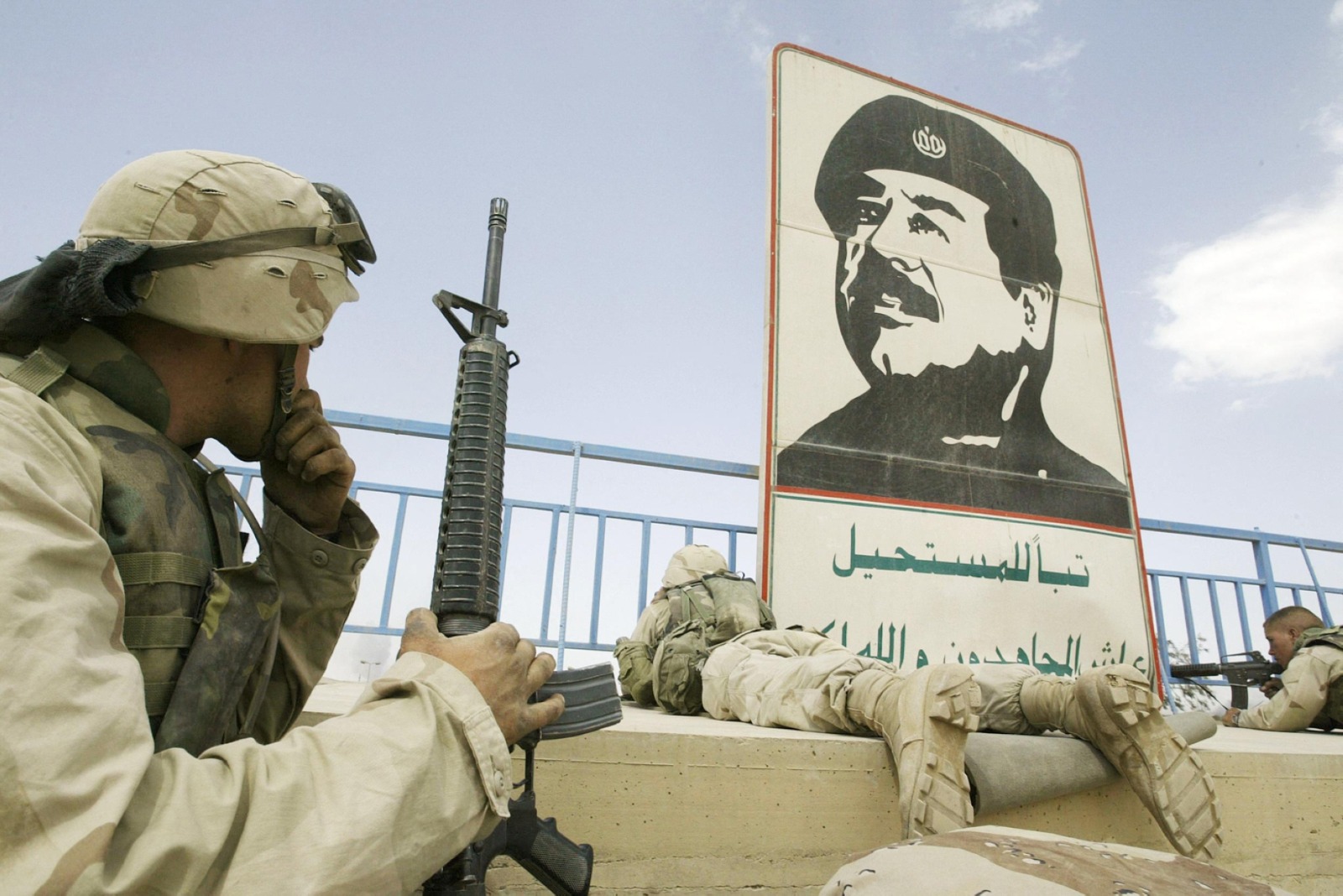 جنود من فرقة المشاة البحرية الأميركية بالقرب من صورة صدام حسين في ملعب ببغداد، 10 أبريل 2003