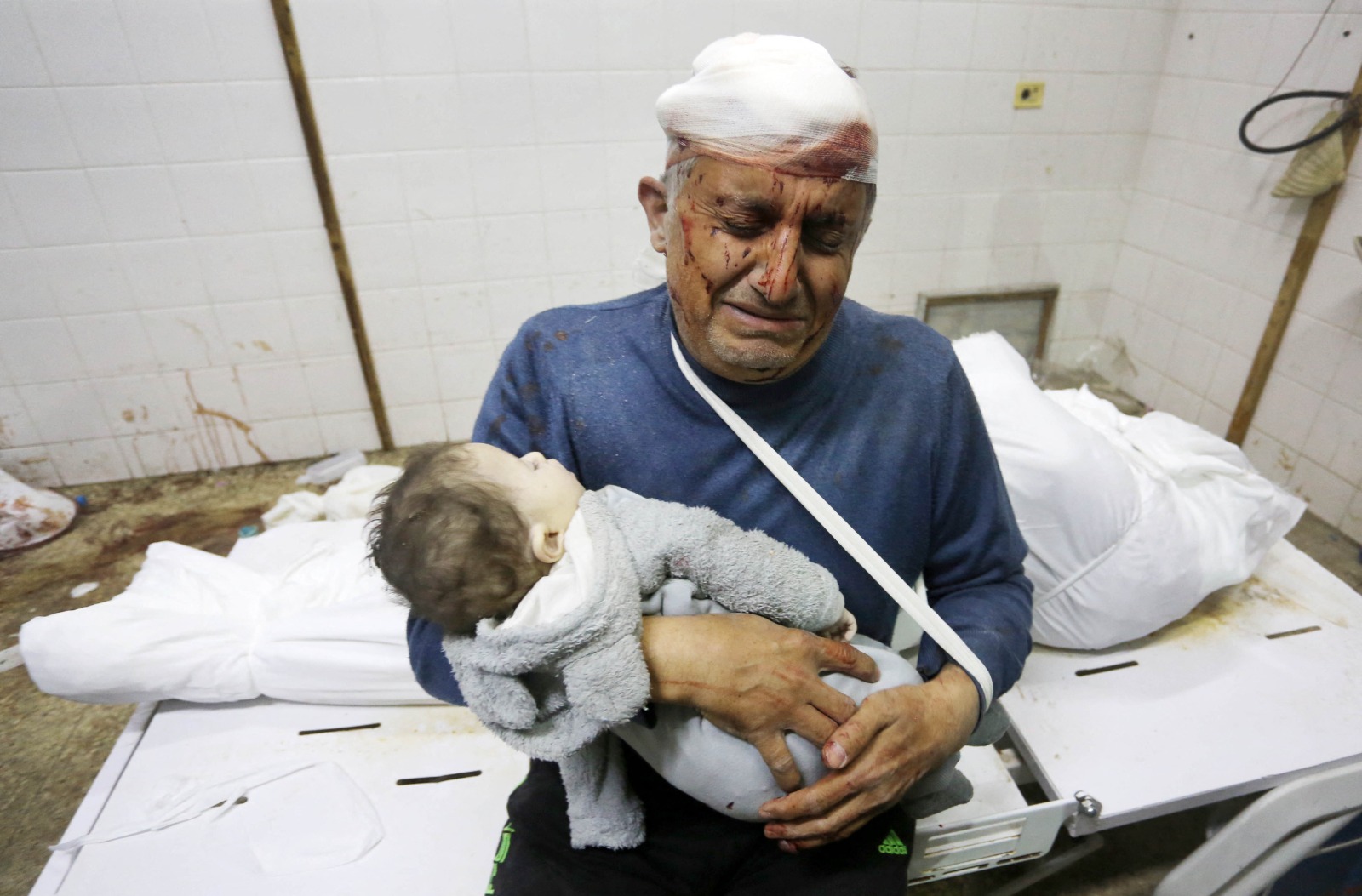 رجل فلسطيني يحمل جثة طفل في مستشفى شهداء الأقصى بعد الهجوم الإسرائيلي على دير البلح، غزة. 6 يناير 2024