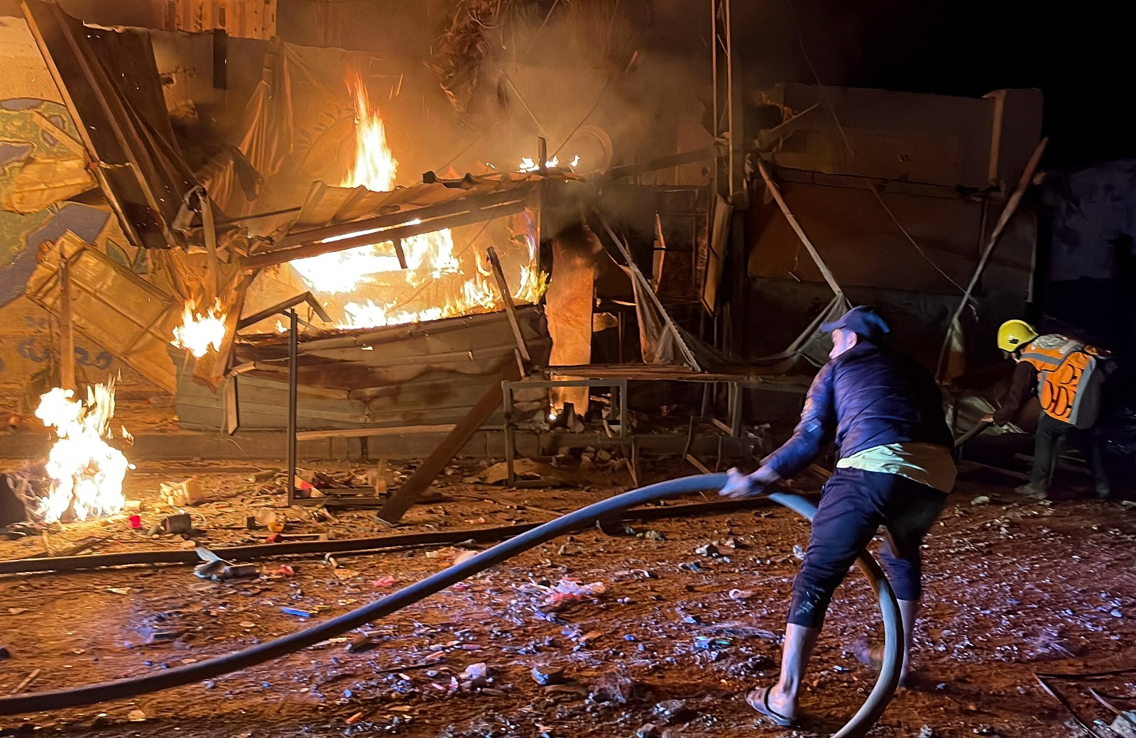 فلسطينيون يحاولون إطفاء حريق بعد غارة إسرائيلية على مدرسة للأونروا تؤوي نازحين في مخيم البريج وسط قطاع غزة. 6 مايو 2025