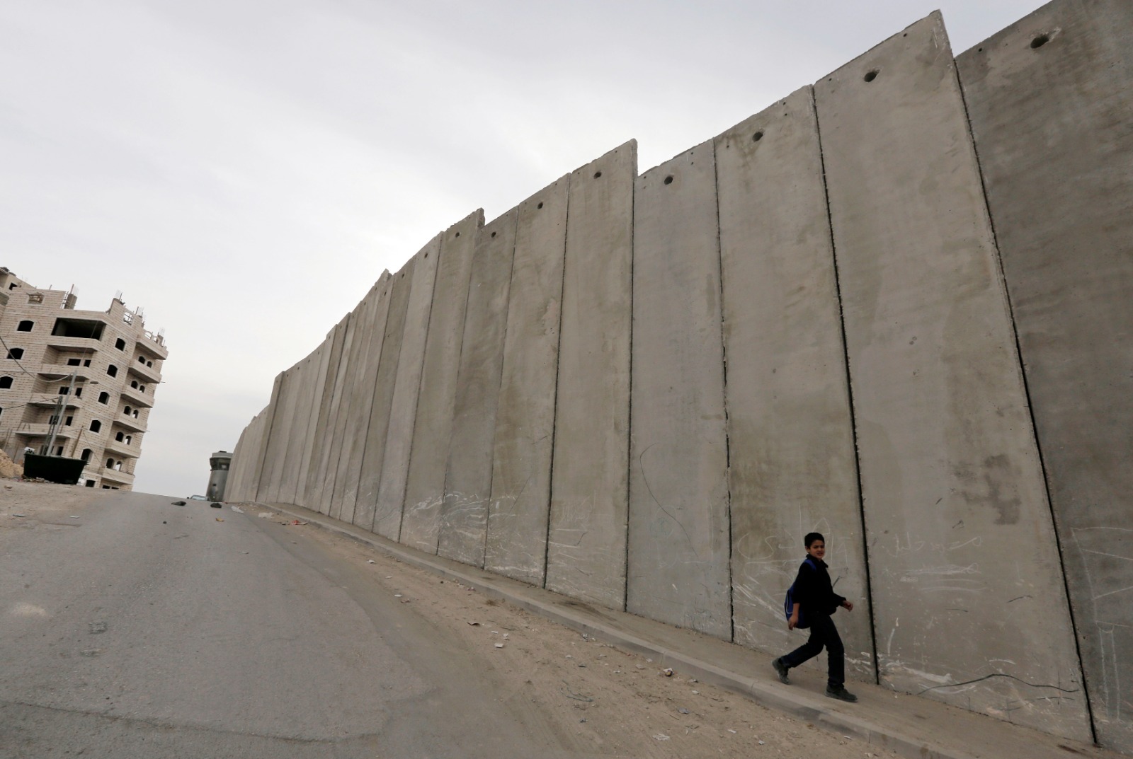 صبي فلسطيني يمر بجوار جزء من الجدار الإسرائيلي العازل في الضفة الغربية بالقرب من القدس المحتلة. 23 نوفمبر 2013