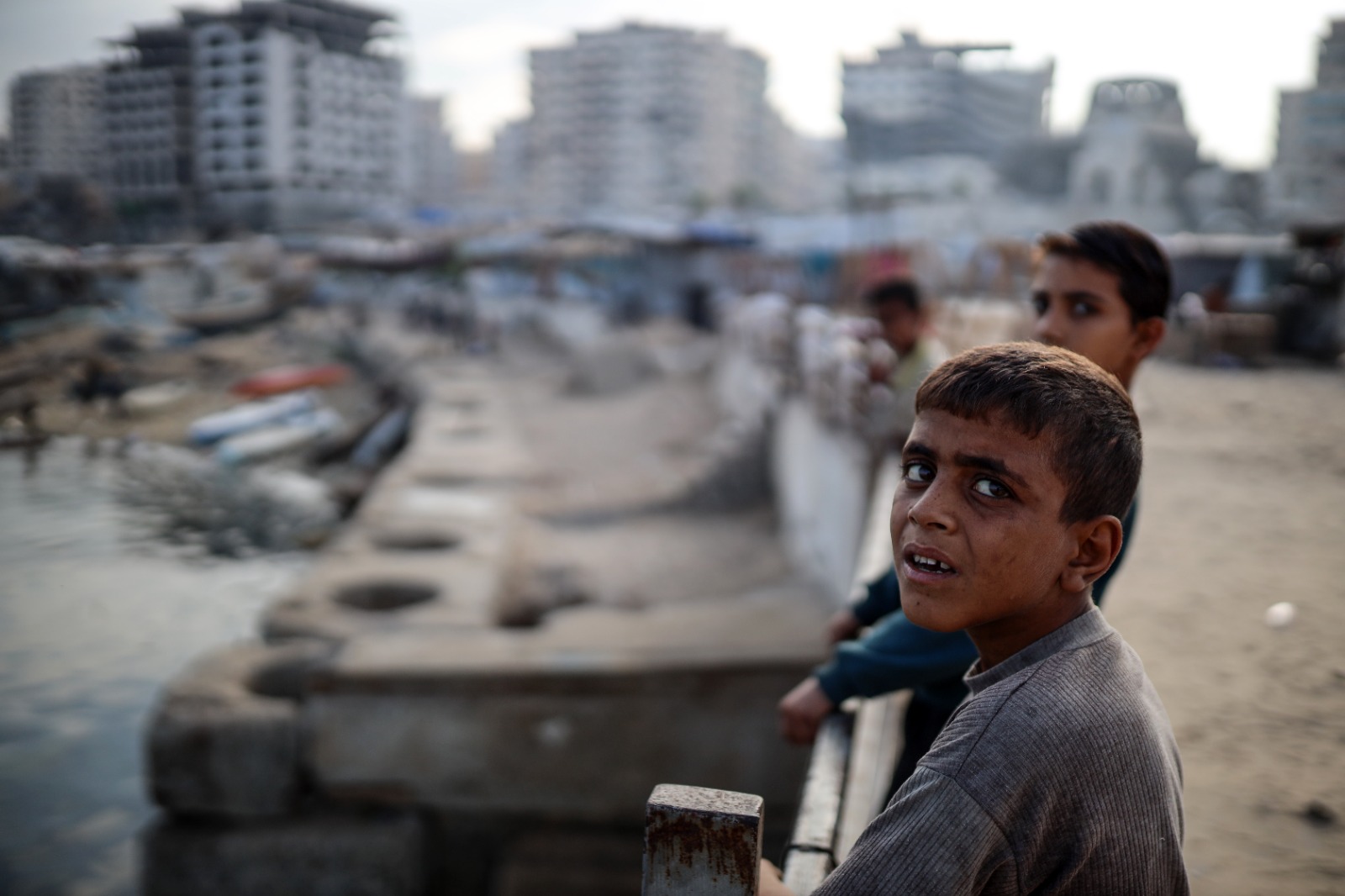 'أطفال فلسطينيون مشردون يقفون خارج خيمتهم في مخيم نزوح قرب ميناء غزة، 19 أكتوبر 2025'