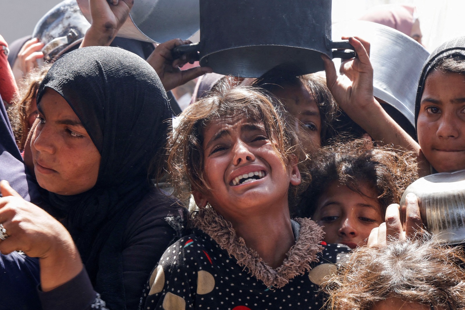 طفلة فلسطينية تبكي خلال محاولتها الحصول على طعام أعدته جمعية خيرية في خان يونس، جنوب قطاع غزة. 29 أبريل 2025