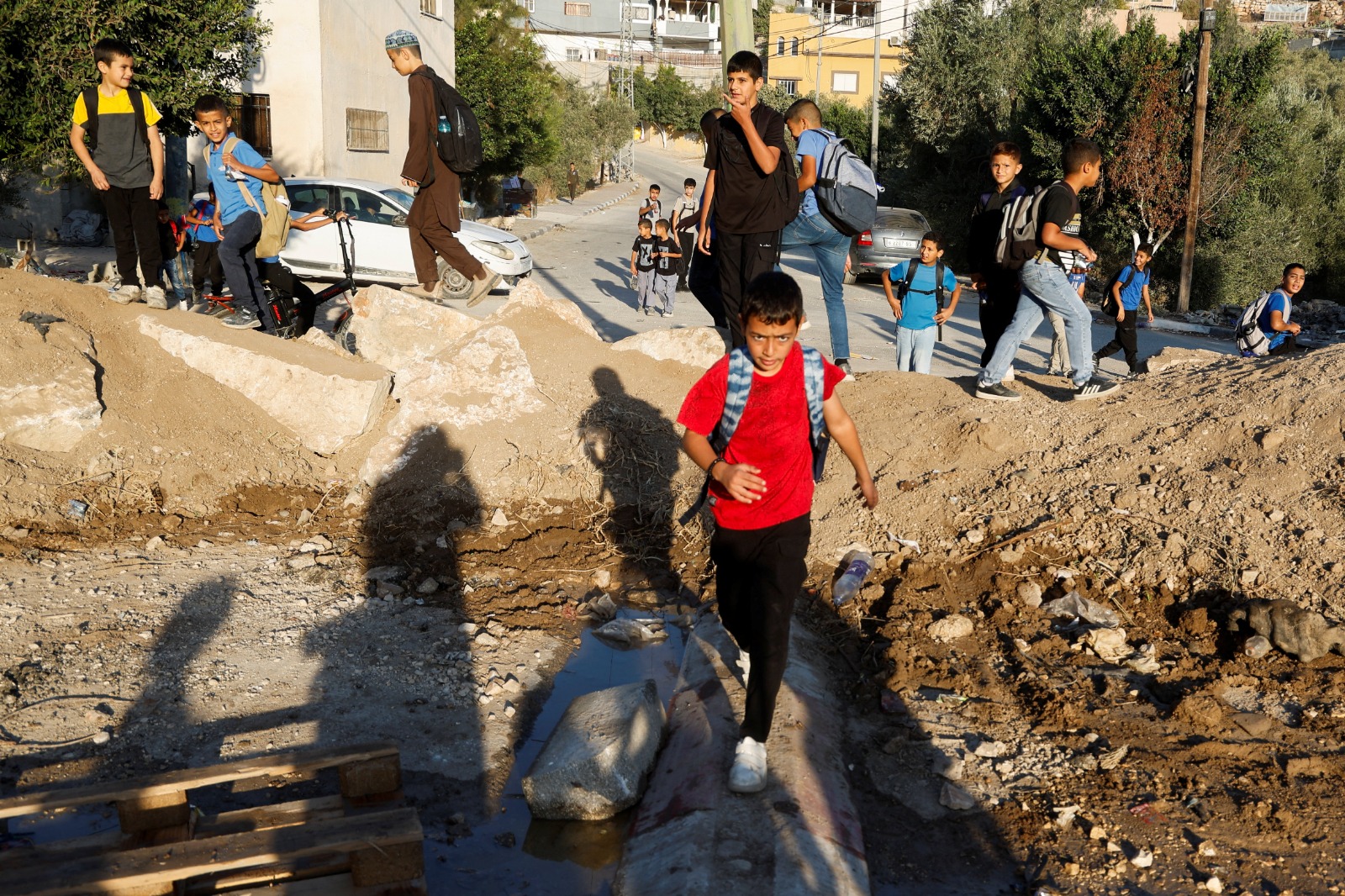 طلاب فلسطينيون يحاولون المرور عبر حاجز ترابي وضعته قوات إسرائيلية للوصول إلى مدرستهم في جنين بالضفة الغربية المحتلة. 8 أكتوبر 2025